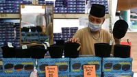 Seorang pedagang memajang topi songkok tradisional Melayu untuk dijual di pasar temporer yang didirikan selama bulan suci Ramadan di distrik Geylang Serai di Singapura, 10 April 2023.
