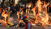 Seorang pria berjalan melewati patung yang terbakar selama pembakaran tradisional Yudas, bagian dari perayaan Pekan Suci Paskah, di Caracas, Venezuela, Minggu (9/4/2023). REUTERS/GABY ORAA
