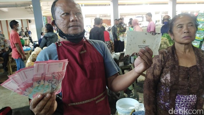Pedagang Pasar Legi Solo menunjukkan uang BLT yang diterimanya dari Presiden Jokowi, Senin (10/4/2023).