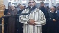 Barulah selanjutnya, ia tiba-tiba melompat ke arah badan sang imam. Meskipun “dijahili” oleh kucing tersebut, Syekh Walid Mehsas sama sekali tak terdistraksi dan lanjut melantunkan bacaan surahnya. (Foto: Facebook/The Official Page of the Reciter Walid Mehsas)