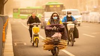 Warga mengendarai sepeda listrik dalam badai pasri di Hothot, China. Ding Genhou/VCGGetty Images