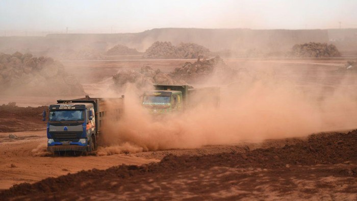 'Hujan Debu' Proyek Bandara Raksasa Vietnam Landa Permukiman dan Sekolah This aerial photograph taken on April 5, 2023 shows dust being thrown up by trucks carrying soil at the construction site of Long Thanh airport in Dong Nai province. - Red dust from the construction of a huge airport in Vietnam has rained down on thousands of people nearby for months, residents told AFP, coating trees, homes and schoolyards in a thick layer of dirt. (Photo by Nhac NGUYEN / AFP) (Photo by NHAC NGUYEN/AFP via Getty Images)