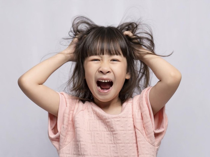 Angry Asian girl on white background, angry child, frantic gesture expression and put his hand on his head.