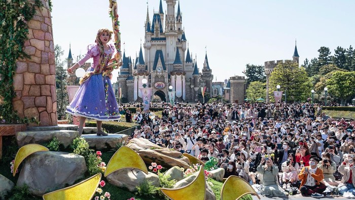 A performer waves as he takes part in a new daytime parade to mark the 40th anniversary of Tokyo Disneyland in Urayasu, in suburban Tokyo on April 10, 2023. (Photo by Richard A. Brooks / AFP) (Photo by RICHARD A. BROOKS/AFP via Getty Images)