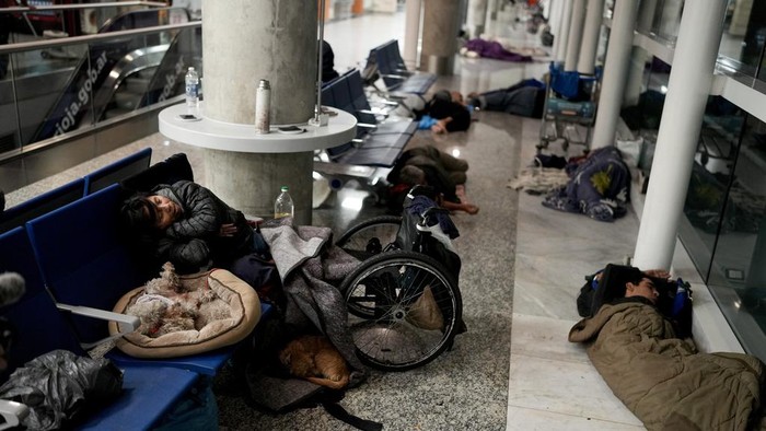 Laura Cardozo, left, sleeps with her two dogs at the Jorge Newbery international airport, commonly known as Aeroparque, in Buenos Aires, Argentina, Thursday, April 6, 2023. Despite the bustling activity of passengers, over 100 homeless people sleep at Aeroparque each night. (AP Photo/Natacha Pisarenko)