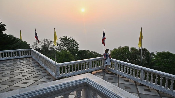 A visitor looks out at high levels of air pollution from the top of Doi Suthep temple in Chiang Mai on April 11, 2023. - Northern Thailand has been choking on heavy air pollution since the start of the year, caused in part by seasonal agricultural burning. (Photo by Lillian SUWANRUMPHA / AFP) (Photo by LILLIAN SUWANRUMPHA/AFP via Getty Images)