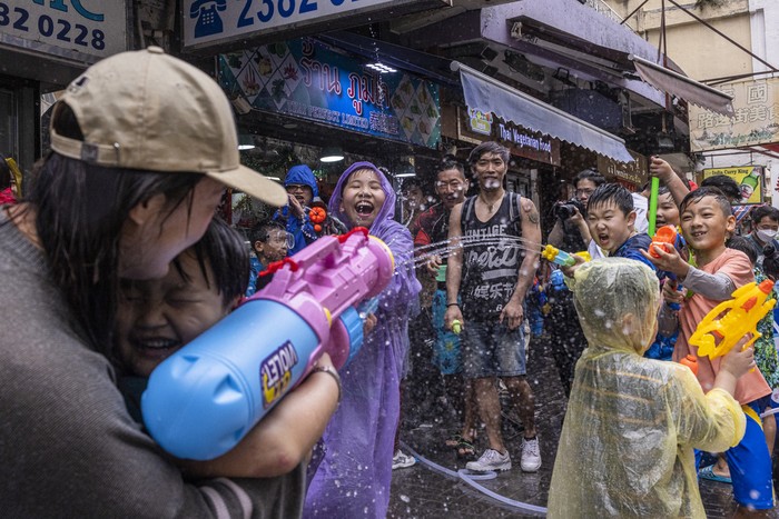 Revellers splash water on police officers during celebrations for the Songkran festival in Hong Kong, Sunday, April 9, 2023. (AP Photo/Louise Delmotte)