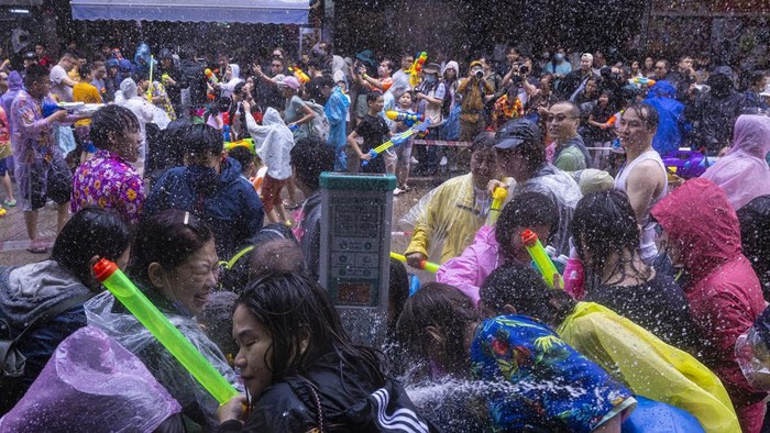 Semarak Perang Air Kembali ke Jalanan Hong Kong, Pertama Sejak Pandemi Revellers splash water on police officers during celebrations for the Songkran festival in Hong Kong, Sunday, April 9, 2023. (AP Photo/Louise Delmotte)