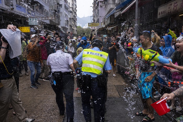 Revellers splash water on police officers during celebrations for the Songkran festival in Hong Kong, Sunday, April 9, 2023. (AP Photo/Louise Delmotte)