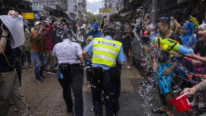 Revellers splash water on police officers during celebrations for the Songkran festival in Hong Kong, Sunday, April 9, 2023. (AP Photo/Louise Delmotte)