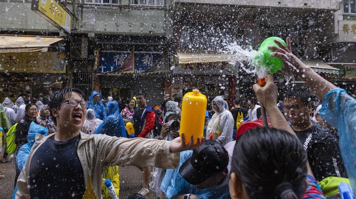 Semarak Perang Air Kembali ke Jalanan Hong Kong, Pertama Sejak Pandemi Revellers splash water on police officers during celebrations for the Songkran festival in Hong Kong, Sunday, April 9, 2023. (AP Photo/Louise Delmotte)