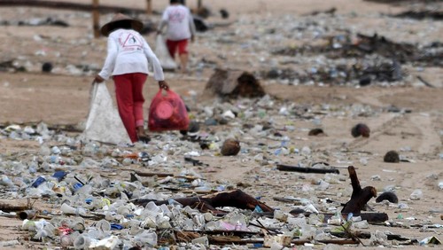 Trash collectors remove plastic and other debris washed ashore at Kedonganan Beach, Badung regency, on Indonesias resort island of Bali on April 12, 2023. (Photo by SONNY TUMBELAKA / AFP) (Photo by SONNY TUMBELAKA/AFP via Getty Images)