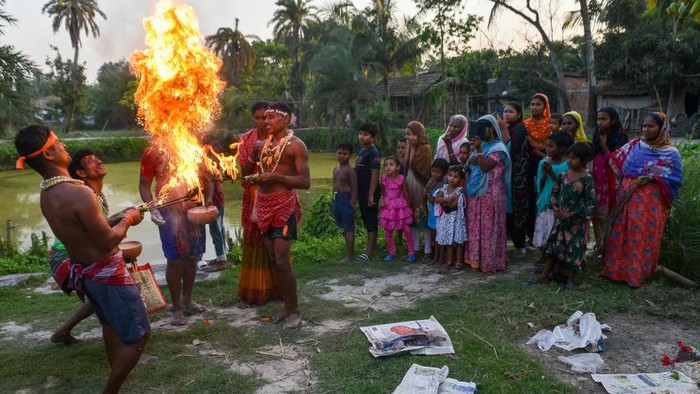 Devotees are seen throwing flames as prayer offering to Lord Shiva during Gajon festival in a village 100 kilometers from Kolkata , India , on 12 April 2023 . Gajon festival is a Hindu festival celebrated on the last day of Bengali month of Chaitra and is done to honor lord Shiva . Devotees dresses themselves in flower and throws dry powder which spews fire from a cauldron to offer prayers to Lord Shiva during this time.  (Photo by Debarchan Chatterjee/NurPhoto via Getty Images)