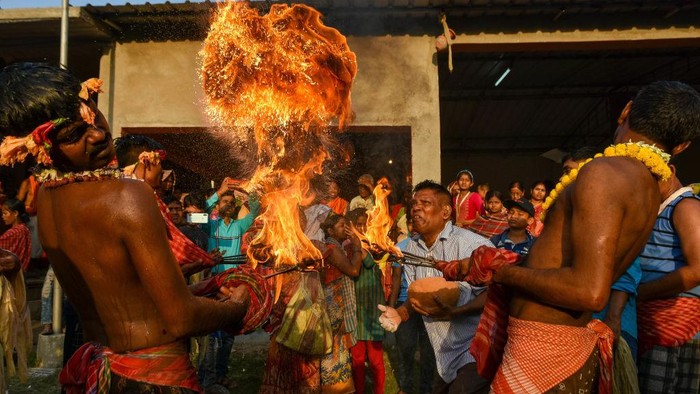 Atraksi Lempar Api Ramaikan Festival Gajon India Devotees are seen throwing flames as prayer offering to Lord Shiva during Gajon festival in a village 100 kilometers from Kolkata , India , on 12 April 2023 . Gajon festival is a Hindu festival celebrated on the last day of Bengali month of Chaitra and is done to honor lord Shiva . Devotees dresses themselves in flower and throws dry powder which spews fire from a cauldron to offer prayers to Lord Shiva during this time. (Photo by Debarchan Chatterjee/NurPhoto via Getty Images)