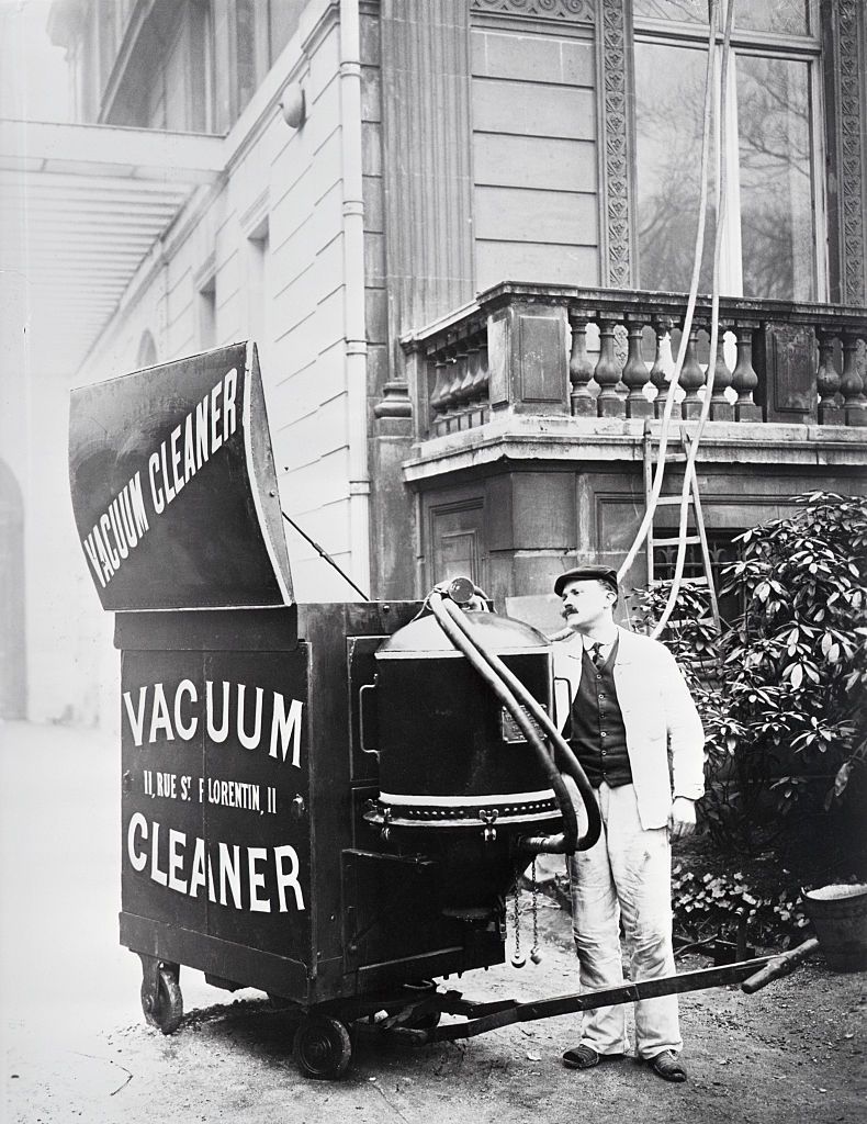 Mesin Penyedot Debu Pertama (Original Caption) Beginning of the vacuum cleaner. Movable gadget as wheeled up to house for a cleaning job, ca. 1900, photograph. BPA 2 #5184