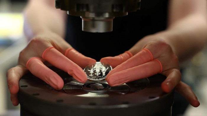 Penampakan Koin Perayaan Penobatan Raja Charles III Factory worker, Jason, checks a commemorative 50 pence coin after pressing, in Llantrisant, Britain, April 12, 2023. The coin is unveiled by The Royal Mint to celebrate the upcoming coronation of King Charles III. REUTERS/Molly Darlington