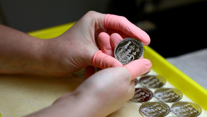 Factory worker, Jason, checks a commemorative 50 pence coin after pressing, in Llantrisant, Britain, April 12, 2023. The coin is unveiled by The Royal Mint to celebrate the upcoming coronation of King Charles III. REUTERS/Molly Darlington