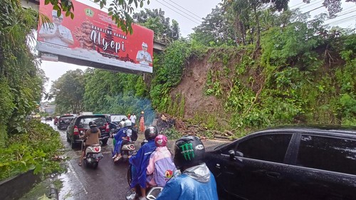Proses penanganan tebing longsor dan pohon tumbang di pinggir Jalan Gatot Subroto, Desa Banjaranyar, Kecamatan Kediri, Kamis (13/4/2023). Di saat yang sama, separo jalan telah bisa dilalui pengguna kendaraan. (chairul amri simabur/detikBali)
