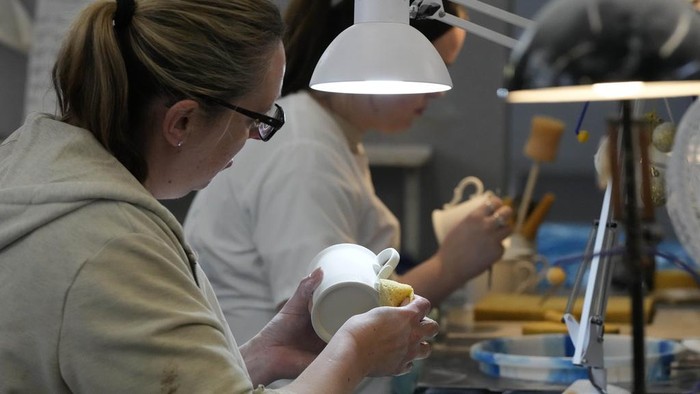 A worker paints the finish on official chinaware in a pottery in Stoke on Trent, Thursday, April 13, 2023. A range of official chinaware produced in Stoke-on-Trent by Royal Collection Trust, a department of the Royal Household, will go on sale on Friday, April 14 to commemorate the upcoming Coronation on May 6, 2023. (AP Photo/Frank Augstein, pool)