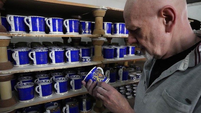 A worker paints the finish on official chinaware in a pottery in Stoke on Trent, Thursday, April 13, 2023. A range of official chinaware produced in Stoke-on-Trent by Royal Collection Trust, a department of the Royal Household, will go on sale on Friday, April 14 to commemorate the upcoming Coronation on May 6, 2023. (AP Photo/Frank Augstein, pool)