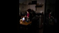 Keluarga Zulfaqaar Seedat (kanan) dan Kurshaid Shaik (kiri) menggunakan lampu portabel untuk menerangi dapur mereka selama pemadaman bergilir sambil berbagi makanan saat Sahur di Robertsham, Johannesburg, Rabu (12/4/2023).  
