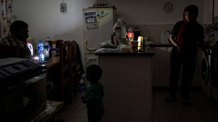 Krisis Energi Bikin Ramadan di Afrika Selatan Gelap Gulita The family of Zulfaqaar Seedat (L) and Kurshaid Shaik (R) use portable lamps to brighten their kithchen during rolling blackouts while sharing a meal at the time of Sehri (also called Suhoor), the meal consumed early in the morning by Muslims during the month of Ramadan before sunrise, in Robertsham, Johannesburg, on 12 April 2023. - Scheduled blackouts, known as loadshedding, have burdened Africa's most industrialised economy for years, with its state-owned energy firm Eskom failing to keep pace with demand and maintain its ageing coal power infrastructure. (Photo by Shiraaz Mohamed / AFP) (Photo by SHIRAAZ MOHAMED/AFP via Getty Images)