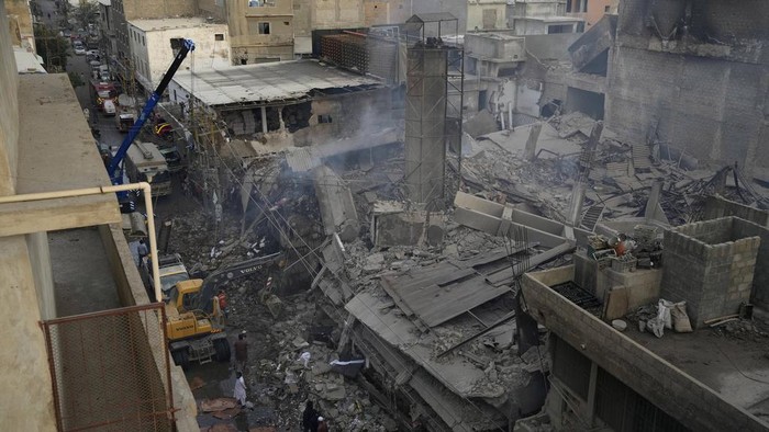 Paramilitary soldier and police officers gather at the site of a fire in Karachi, Pakistan, Thursday, April 13, 2023. A massive fire broke out in a garment factory in the southern Pakistan port city of Karachi. The cause of the blaze, which ripped through the factory Wednesday night and eventually caused it to collapse, was not immediately known, rescue officials and police said. (AP Photo/Fareed Khan)