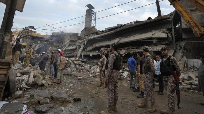 Paramilitary soldier and police officers gather at the site of a fire in Karachi, Pakistan, Thursday, April 13, 2023. A massive fire broke out in a garment factory in the southern Pakistan port city of Karachi. The cause of the blaze, which ripped through the factory Wednesday night and eventually caused it to collapse, was not immediately known, rescue officials and police said. (AP Photo/Fareed Khan)