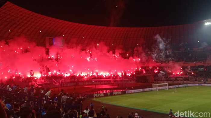 Bobotoh menyalakan flare usai Persib telan kekalahan di Stadion GBLA, Sabtu (15/4/2023).