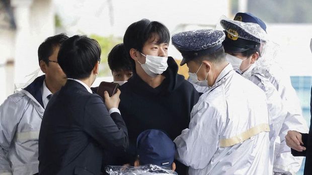 A man, believed to be a suspect who threw a pipe-like object near Japanese Prime Minister Fumio Kishida during his outdoor speech, is held by police officers at Saikazaki fishing port in Wakayama, Wakayama Prefecture, south-western Japan April 15, 2023, in this photo released by Kyodo. Mandatory credit Kyodo via REUTERS