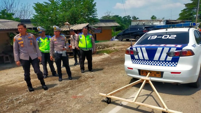Polisi saat menyapu ranjau paku di jalur arteri Kabupaten Karawang, Sabtu (15/4/2023).