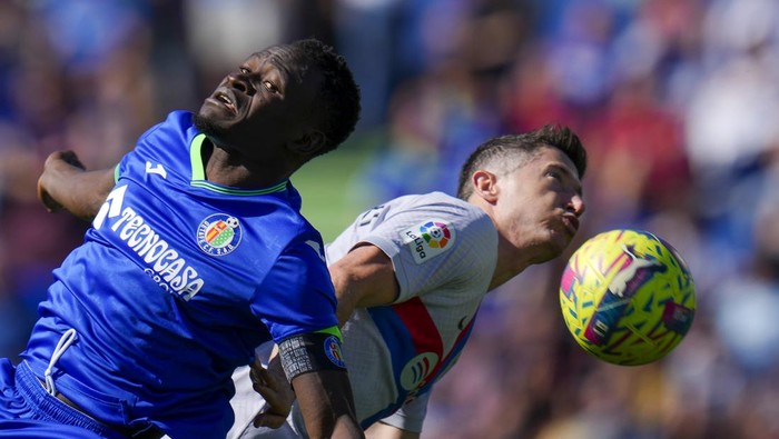 Getafes Djene Dakonam, left, fights for the ball with Barcelonas Robert Lewandowski during a Spanish La Liga soccer match between Getafe and FC Barcelona at the Coliseum Alfonso Perez stadium in Getafe, Spain, Sunday, April 16, 2023. (AP Photo/Manu Fernandez)