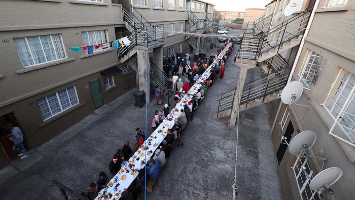 People sit at a long makeshift table before an Iftar, breaking of the fast, during the holy month of Ramadan in Heideveld on the Cape Flats, Cape Town, South Africa, April 15, 2023. REUTERS/Esa Alexander