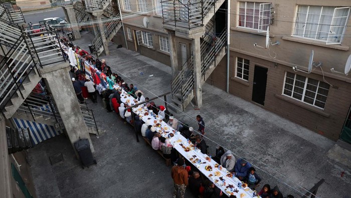 People sit at a long makeshift table before an Iftar, breaking of the fast, during the holy month of Ramadan in Heideveld on the Cape Flats, Cape Town, South Africa, April 15, 2023. REUTERS/Esa Alexander