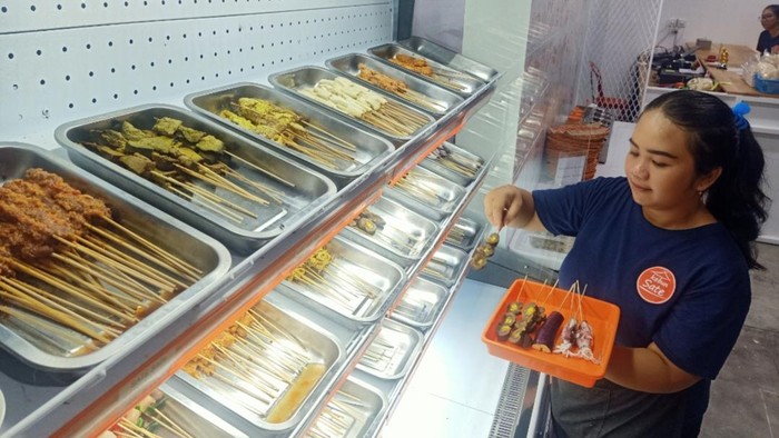 Salah satu pegawai Kebun Sate tampak mengambil beberapa sate di Kebun Sate, Jalan Genetri V No 1 B Denpasar, Bali pada Minggu (16/4/2023). (Ni Made Lastri Karsiani Putri-detikBali)