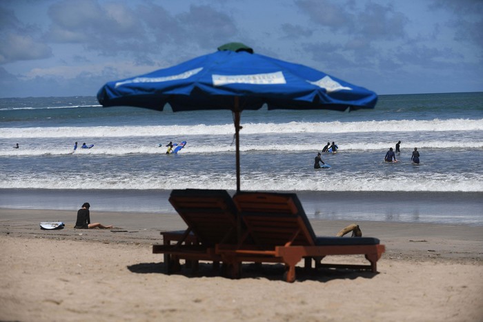 A tourist prepares to go surfing on Kuta Beach in Denpasar, on Indonesia resort island of Bali, on April 16, 2023. (Photo by SONNY TUMBELAKA / AFP) (Photo by SONNY TUMBELAKA/AFP via Getty Images)