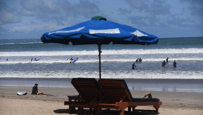 A tourist prepares to go surfing on Kuta Beach in Denpasar, on Indonesia resort island of Bali, on April 16, 2023. (Photo by SONNY TUMBELAKA / AFP) (Photo by SONNY TUMBELAKA/AFP via Getty Images)