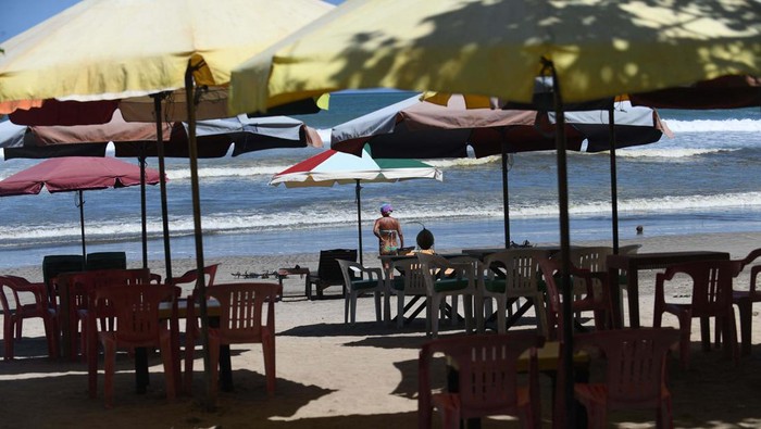 A tourist prepares to go surfing on Kuta Beach in Denpasar, on Indonesia resort island of Bali, on April 16, 2023. (Photo by SONNY TUMBELAKA / AFP) (Photo by SONNY TUMBELAKA/AFP via Getty Images)