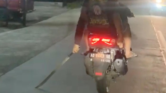 Tangkapan layar pemuda naik motor membawa senjata tajam di jalanan di Sragen. Foto diunggah Minggu (16/4/2023).