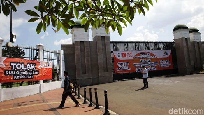 Gerbang DPR Dipasangi Baliho Tolak UU Cipta Kerja Pejalan kaki melitas dekat gerbang komplek parlemen DPR RI yang dipasangi baliho penolakan UU Cipta Kerja , Jakarta, Senin (17/4/2023). Partai Buruh menolak UU Cipta Kerja, selanjutnya para buruh menuntut pemerintah mencabut parliamentary threshold atau ambang batas parlemen. mereka juga menuntut agar DPR segera mengesahkan RUU Perlindungan Pekerja Rumah Tangga (PPRT) menjadi Undang-Undang