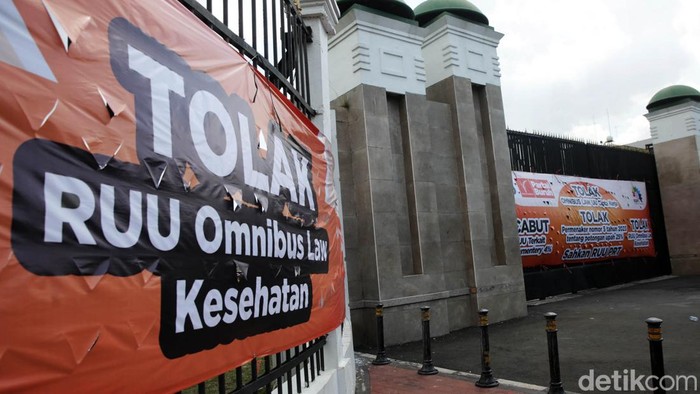 Pejalan kaki melitas dekat gerbang komplek parlemen DPR RI yang dipasangi baliho penolakan UU Cipta Kerja , Jakarta, Senin (17/4/2023). Partai Buruh menolak UU Cipta Kerja, selanjutnya para buruh menuntut pemerintah mencabut parliamentary threshold atau ambang batas parlemen. mereka juga menuntut agar DPR segera mengesahkan RUU Perlindungan Pekerja Rumah Tangga (PPRT) menjadi Undang-Undang