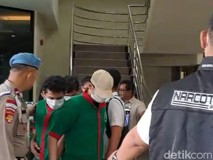 Hud Filbert bertopi dan berbaju tahanan warna hijau saat dirilis polisi
