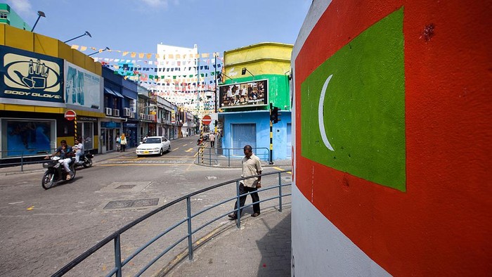 Maldives MALDIVES - DECEMBER 07: People walk past the Maldivian flag painted on a wall in Male, the Maldives, on Sunday, Dec. 7, 2008. Island countries from Grenada in the Caribbean to the Maldives in the Indian Ocean told delegates at the United Nations climate-change talks in early Dec. that their lands may be swamped by rising seas and more powerful storms unless global warming is curbed. (Photo by Daniel J. Groshong/Bloomberg via Getty Images)