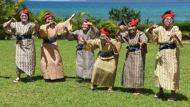 TO GO WITH AFP STORY BY ALASTAIR HIMMERIn this picture taken on June 22, 2015, an elderly women troupe of singers and dancers from Kohama Island in Okinawa wearing traditional local costumes perform at a herb garden on Kohama Island, Okinawa Prefecture. They joke about knocking on heaven's door, but a Japanese 'girl band' named KBG84, with an average age of 84 have struck a blow for grannies everywhere by becoming pop idols. AFP PHOTO / Toru YAMANAKA        (Photo credit should read TORU YAMANAKA/AFP via Getty Images)