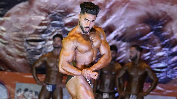 Contestants flex their muscles during a state level body building championship in Jammu, India, Sunday, April 16, 2023. (AP Photo/Channi Anand)