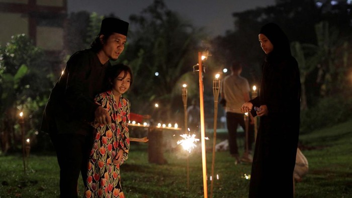 Malaysian Muslim Fadzlie Mohamad, 38, helps his daughter Nurkeisha Ammara, 8, to light a sparkler on the last ten days of Muslim holy month of Ramadan in Kuala Lumpur, Malaysia April 16, 2023. REUTERS/Hasnoor Hussain