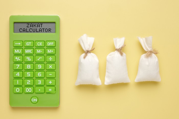 A picture of calculator written Zakat Calculator with 3 rice bags. How to calculate zakat concept.