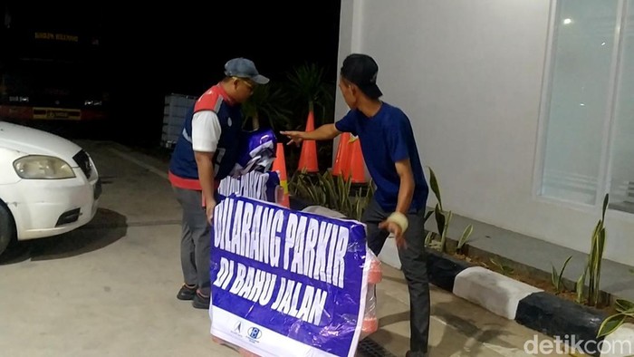 Pekerja menyiapkan rambu larangan parkir di bahu jalan Tol Pekalongan, Selasa (18/4/2023).