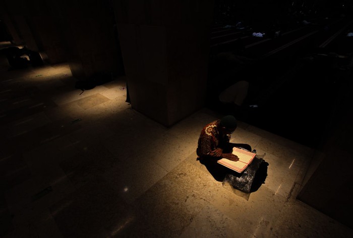 JAKARTA, INDONESIA - APRIL 14: A woman reads the Holy Quran as Muslims perform Itikaf worship during the last ten days of holy month of Ramadan at the Istiqlal Mosque in Jakarta, Indonesia on April 14, 2023. The last 10 days of Ramadan 1444 Hijriah, the Istiqlal Mosque is open 24 hours for Muslims to carry out itikaf or stay silent in the mosque with the intention of getting closer to Allah by means of reading the Holy Quran more, dhikr, remembering self-deficiencies, praying sunnah, and praying until the end Ramadan to get the night of Lailat al-Qadr is the night of the revelation of the Holy Quran which is believed to occur on one of the odd nights in the last 10 days of Ramadan. (Photo by Eko Siswono Toyudho/Anadolu Agency via Getty Images)