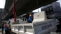 Petugas tampak mengangkut beton barier tersebut dengan truk.